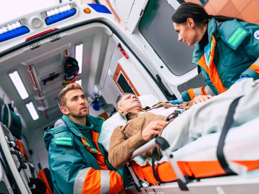 Emergency responders assisting an injured person beside an ambulance equipped with an in-vehicle computer for reliable fleet connectivity
